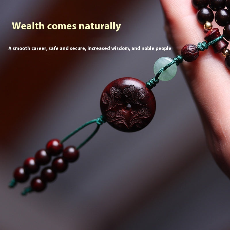 "Talisman carved medallion with jade and red beads, symbolizing prosperity."