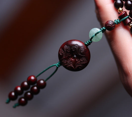 Talisman carved medallion with jade and red beads, symbolizing prosperity.